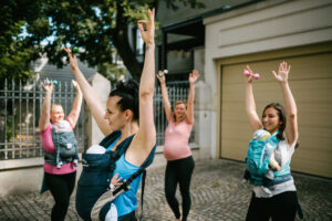 Gruppe von Müttern tanzt Känguru Salsa mit ihren Babys 