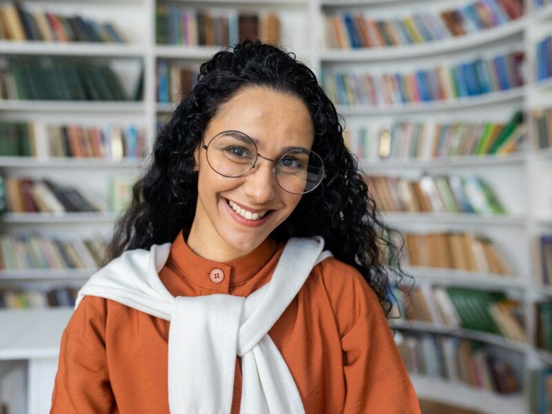 Portrait of young beautiful female student inside university academic library, Hispanic woman with